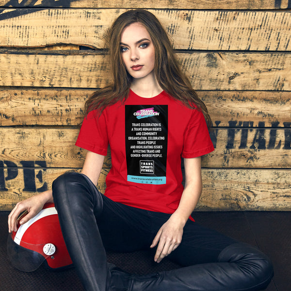 Model in red "Trans Celebration" message t-shirt, seated against a wooden backdrop with a red helmet by her side, promoting trans rights awareness.